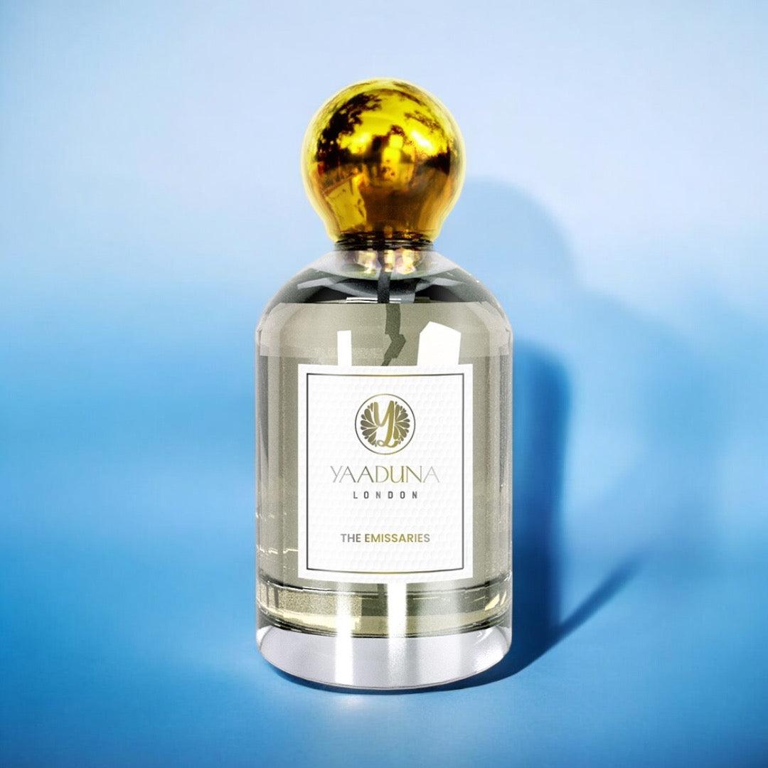 The Emissaries 100ml extrait de parfum bottle with gold cap on blue background, featuring oud and spice notes fragrance by Yaaduna London